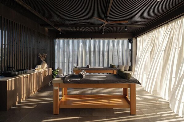 Un interior moderno con una mesa de madera, un sofá y un ventanal con persianas verticales.