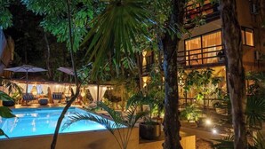 Una piscina rodeada de exuberante vegetación y un edificio con varias ventanas.