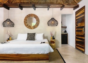 A bedroom with a bed, two wall-mounted lamps, a round mirror, and a wooden door.