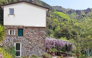 Ein Steinhaus mit weißem Oberteil, einer grünen Tür und einem kleinen Fenster.