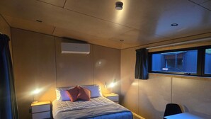 Quarto de hotel com cama, mesas de cabeceira, escrivaninha e janela.