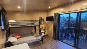 Quarto com beliches, escrivaninha, cadeira, televisão e varanda com vista.