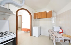 A kitchen with a gas stove, a refrigerator, a microwave, and wooden cabinets. - Cozy apartment in Varese Ligure with WiFi (Varese Ligure)