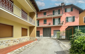 A courtyard with a stone pathway, a green hedge, and a building with a two-story balcony. - Cozy apartment in Varese Ligure with WiFi (Varese Ligure)