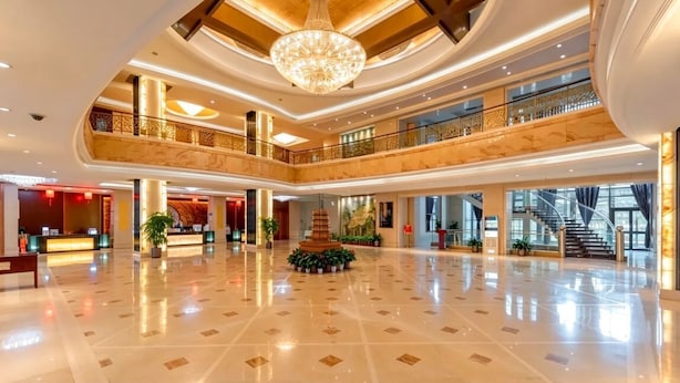 A spacious lobby with a grand chandelier, multiple floors, and a central decorative fountain. - Shanxi International Hotel (Beijing)
