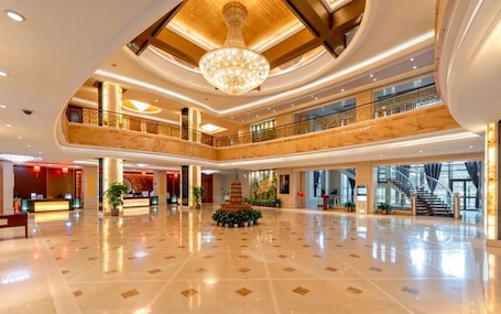A spacious lobby with a grand chandelier, multiple floors, and a central decorative fountain.. shanxidasha
