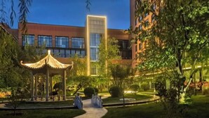 A courtyard with a traditional gazebo, a pathway, and modern buildings in the background. - Shanxi International Hotel (Beijing)