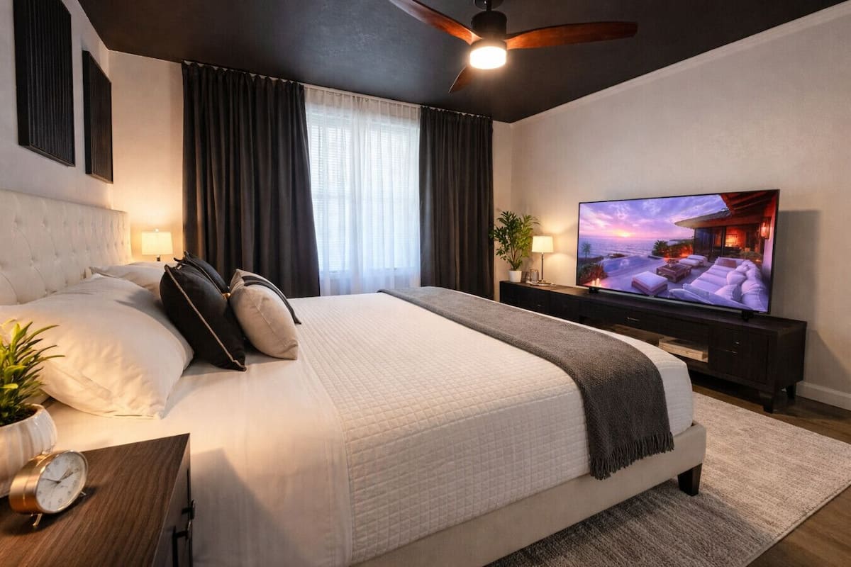 Un dormitorio moderno con una cama grande, un televisor y un ventilador de techo.