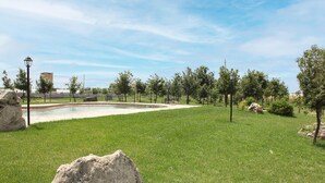 Un'area verde con piscina, alberi e un lampione.