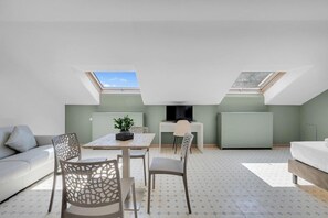 Un espacio habitable moderno y compacto con comedor, televisor y cama.