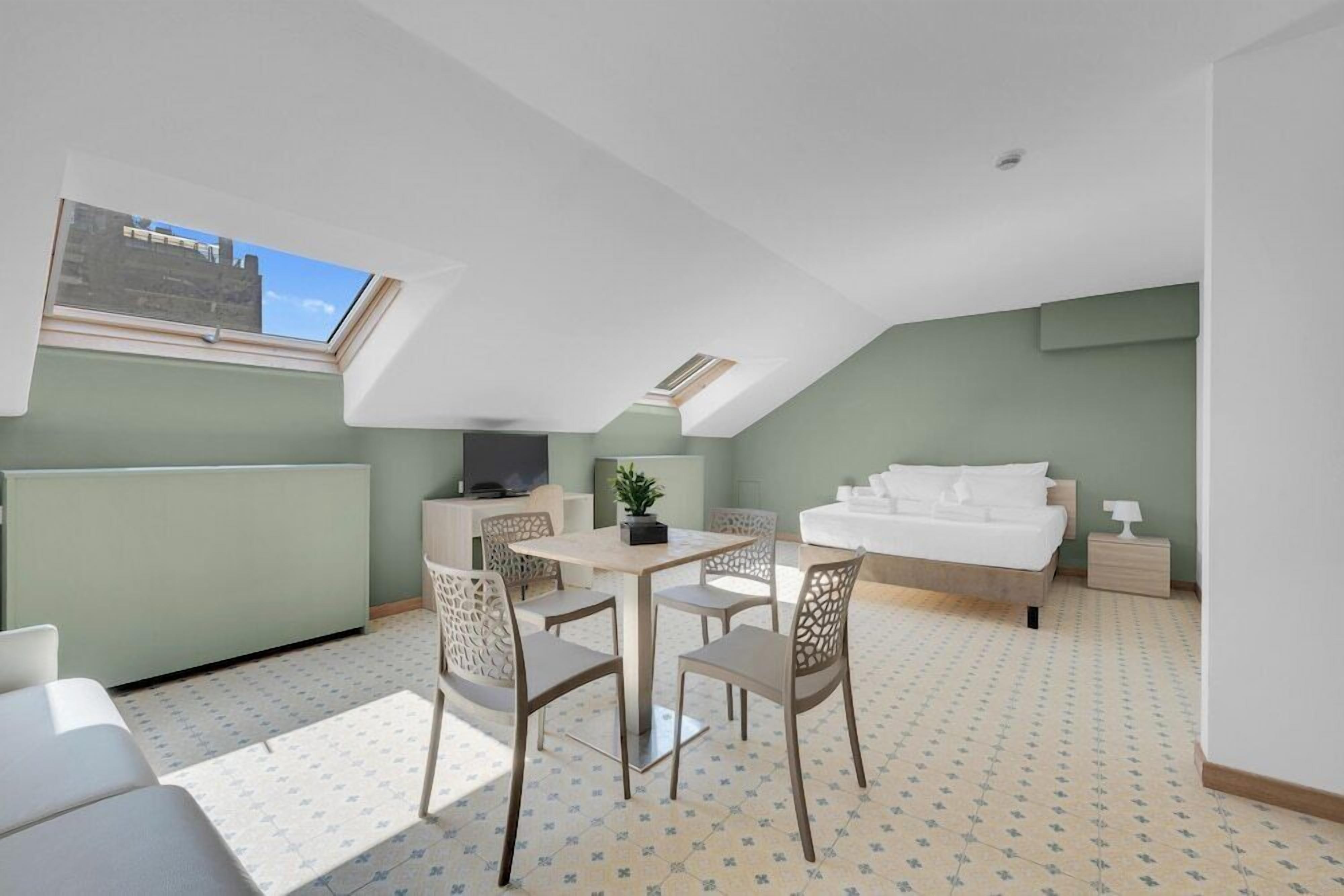 A modern room with a dining area, a bed, and a TV.