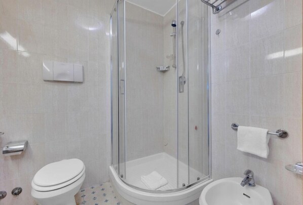 A bathroom with a glass-enclosed shower, a toilet, and a sink.