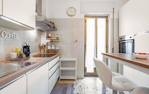 Eine moderne Küche mit einer Kaffeestation, einer Uhr und einem Essbereich mit einem weißen Stuhl.