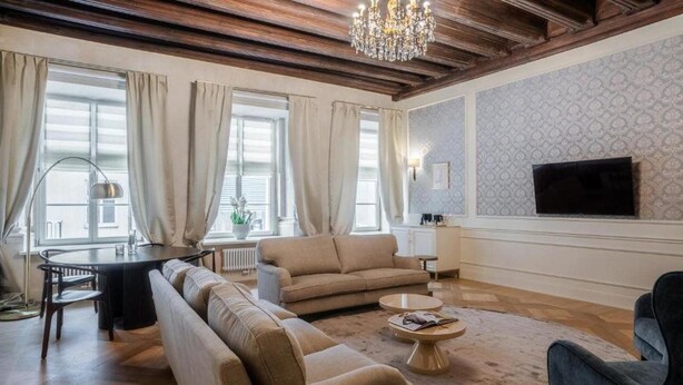 Una sala de estar con sofá, mesa de centro, televisor y candelabro.