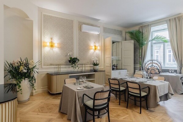 A dining area with tables set for a meal, a large mirror, and a potted plant. - Hotel Unicus Palace (Kraków)
