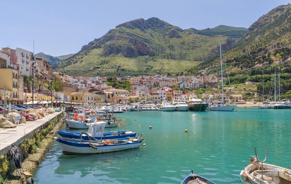 A coastal town with a marina, boats, and buildings along the waterfront.