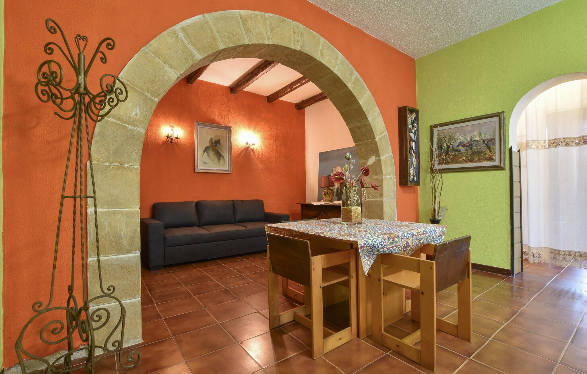A dining area with a table and chairs, a sofa, and an arched doorway.