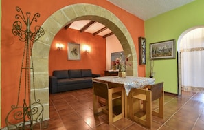 Un espace repas comprenant une table et des chaises, un canapé et une porte en arc de cercle.