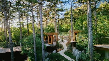 A forested area with two wooden cabins connected by a pathway.