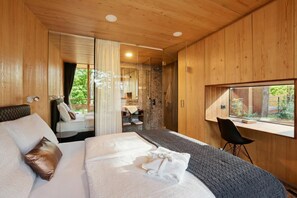 Ein modernes Schlafzimmer mit einem großen Bett, einem Schreibtisch und Blick ins Freie.