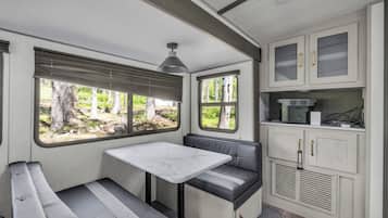 A compact RV kitchen with a dining area, a table, and a bench.