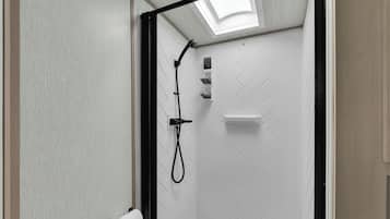 A shower with a black frame, a white herringbone wall pattern, and a skylight.