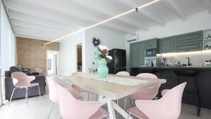A modern kitchen with a dining area, featuring a wooden table, pink chairs, a teal vase, and a black refrigerator. - Amazing home in Salemi (Salemi)