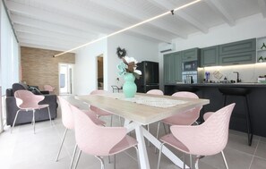 A modern kitchen with a dining area, featuring a wooden table, pink chairs, a teal vase, and a black refrigerator. - Amazing home in Salemi (Salemi)