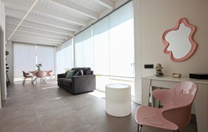 A modern interior with a grey sofa, pink chairs, a white table, and a large window. - Amazing home in Salemi (Salemi)