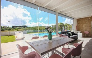 A modern outdoor living area with a pool, a dining table, and seating. - Amazing home in Salemi (Salemi)