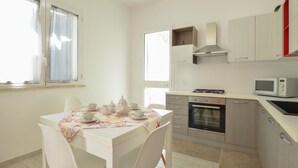 Eine moderne Küche mit weißen Schränken, einem Gasherd, einem Backofen und einer Mikrowelle.