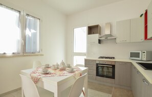 Eine moderne Küche mit weißen Schränken, einem Gasherd, einem Backofen und einer Mikrowelle.
