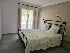 A bedroom with a bed, curtains, a window, and a bedside lamp. - Le Petit Maraîcher: Terrace & Total Tranquility (Puget-sur-Argens)
