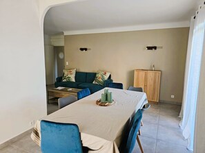 A dining area with a table, chairs, and a sofa in the background. - Le Petit Maraîcher: Terrace & Total Tranquility (Puget-sur-Argens)