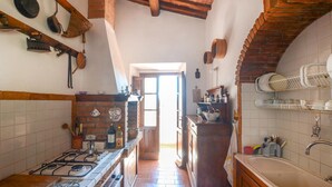 Une cuisine équipée d’une cuisinière à gaz, de meubles de rangement en bois et d’un dosseret carrelé.
