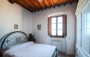 Een slaapkamer met een bed, een raam, een radiator en een deur.