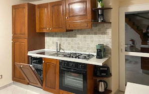 Une cuisine avec des meubles de rangement en bois, une cuisinière à gaz, un lave-vaisselle et une machine à café.