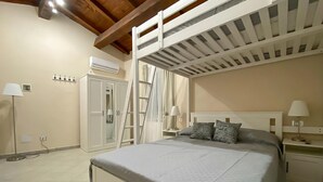 Quarto com cama beliche, guarda-roupa, mesa de cabeceira com abajur e luminária de chão.