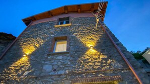 Um edifício de pedra com uma janela e duas luzes fixadas na parede.