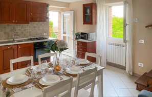 Een keuken met houten kastjes, een eettafel gedekt voor vier personen, en uitzicht op groen.