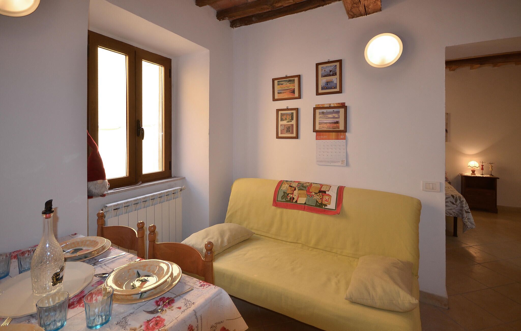 Un saló acollidor amb un sofà, una taula de dinar preparada amb plats i gots, un radiador i quadres emmarcades a la paret.
