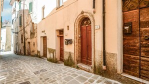 A narrow cobblestone street with buildings featuring arched doorways and numbered windows. - Gorgeous apartment in Monterotondo Marittimo (Monterotondo Marittimo)