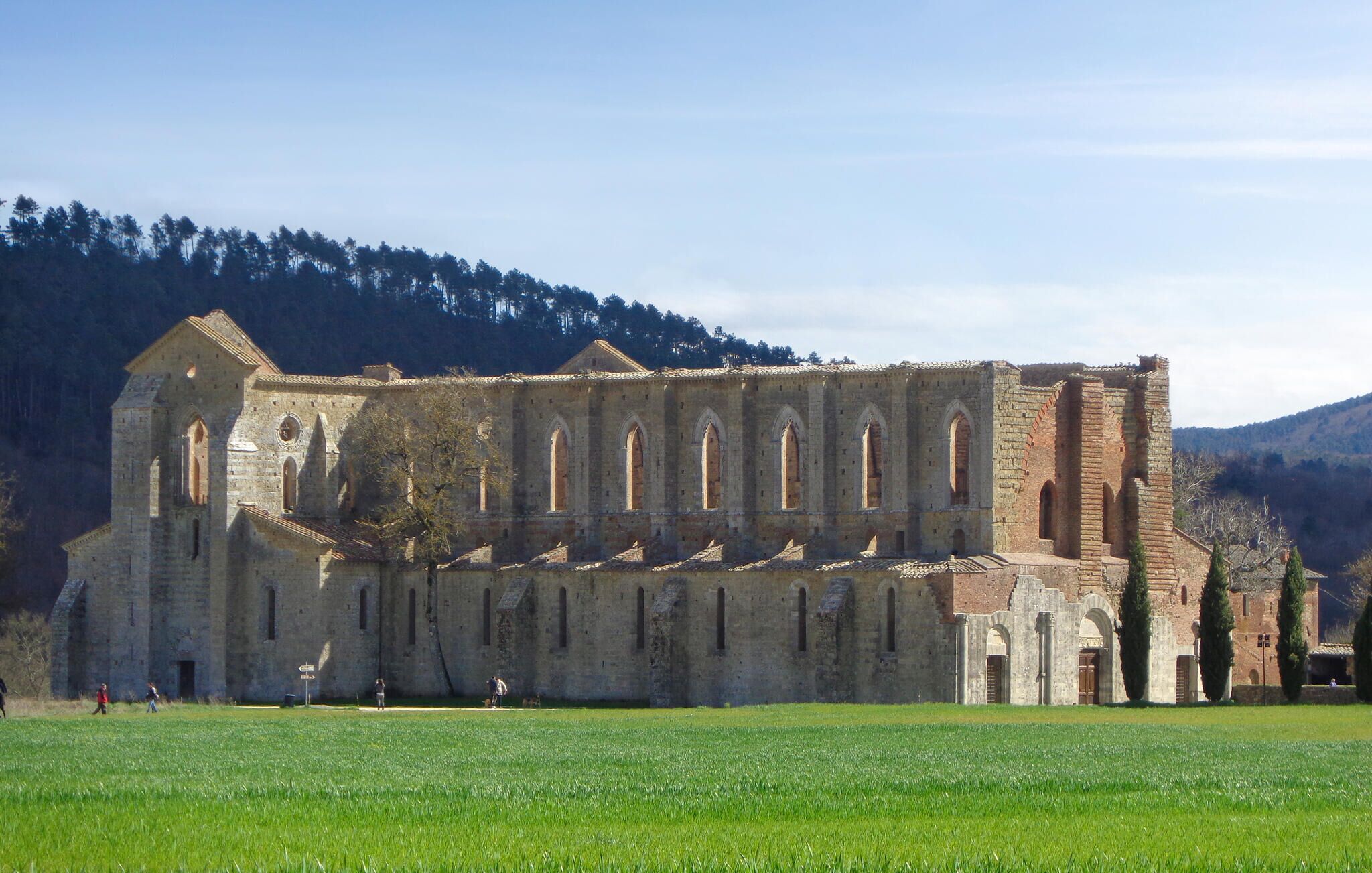 A large, historic stone building with multiple arches and a courtyard.