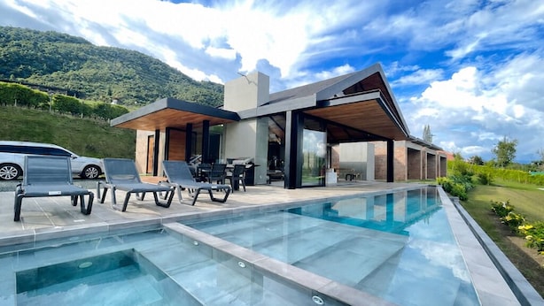 Ein modernes Haus mit Pool, Sitzgelegenheiten im Freien und Blick auf die Berge.