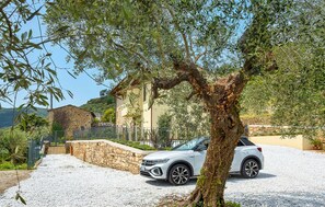 A white SUV parked in front of a stone building with a gravel driveway. - Il Borgo di Badia-L'Oliveta (Buti)