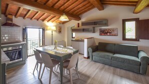 Una cocina con mesa de comedor, sillas, un sofá y un cuadro en la pared.