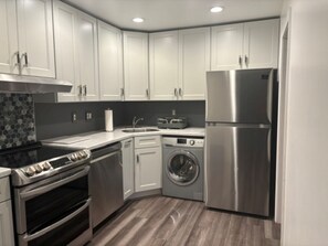 A modern kitchen with stainless steel appliances, white cabinetry, and a built-in washing machine. - Poolside Annapolis Retreat for Mid-Term Stays! (Annapolis)