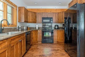 Eine Küche mit Holzausstattung, einem Edelstahlkühlschrank und einem Einbauofen.