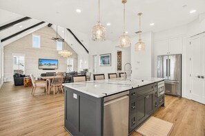 A modern kitchen with a large island, stainless steel appliances, and pendant lighting. - Multilevel beach house with water view, balconies, BBQ and private pool table (Port Aransas)
