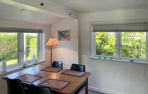Ein Essbereich mit einem Tisch für vier Personen, zwei Stühlen, einer Stehlampe und einem Fenster mit Jalousien.